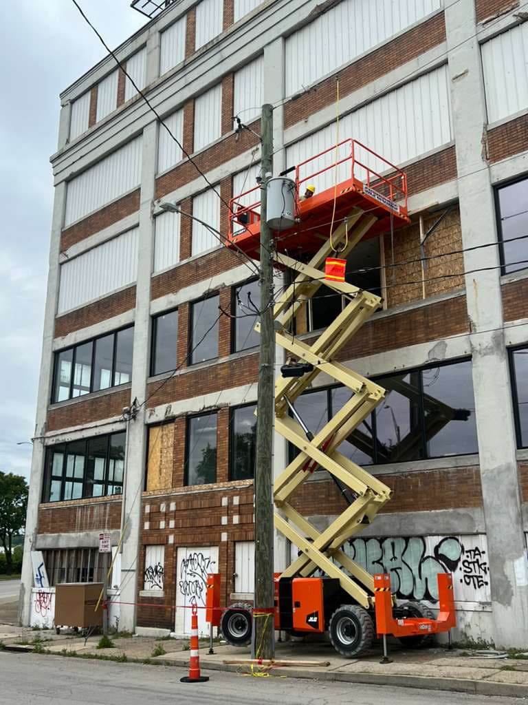 JACOC crew restoring a commercial building exterior from a scissor lift in Cincinnati