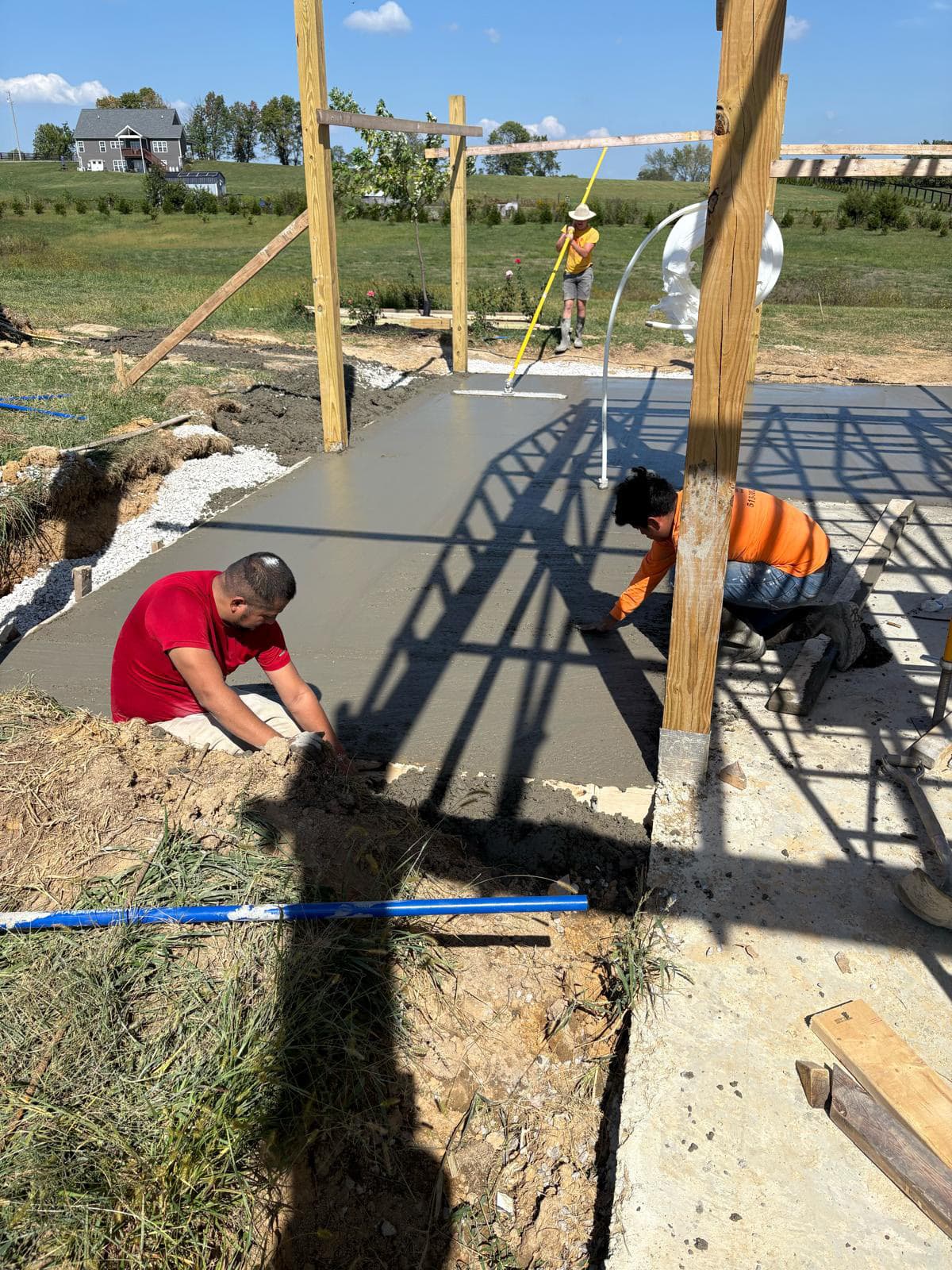 Crew finishing a freshly poured concrete slab on a new construction site